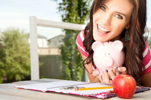A young woman with a piggy bank and financial planner, reviewing student bank accounts.
