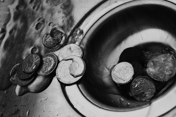 An image of coins going down a drain.