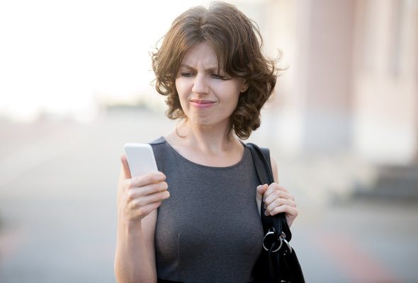 A woman looks at a banking app on her phone.