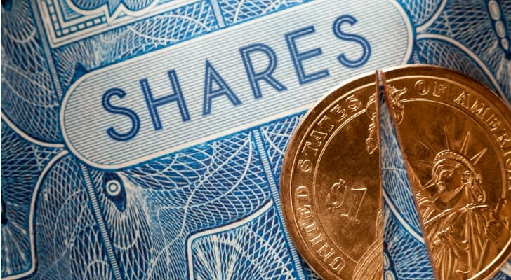 A stock certificate with a one Dollar coin cut to represent the dividend return per share held or, a discounted share purchase price.