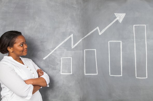 A woman looking at a chart on a board with an upward trend.