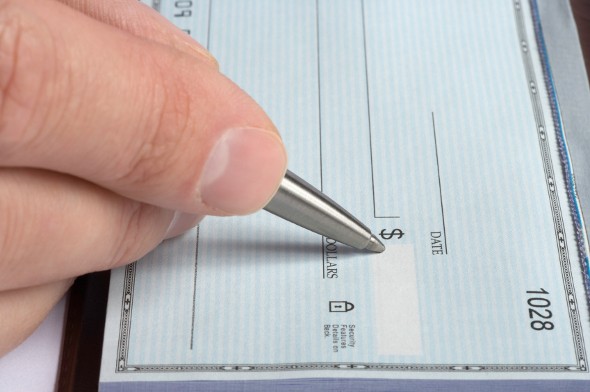 A closeup of a person writing in the amount for a check.