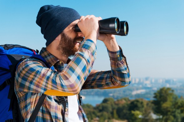 A hiker looks through binoculars.