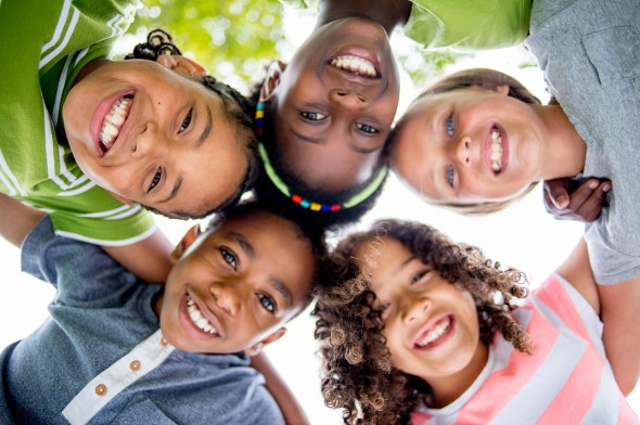 Multiethnic group of children huddling in front of a camera.