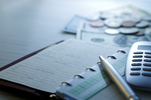 Closeup of a pen and calculator resting on an agenda.