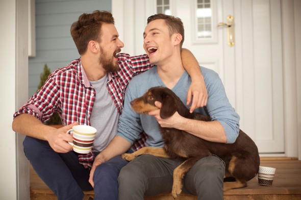 A couple having coffee on their porch with their dog.