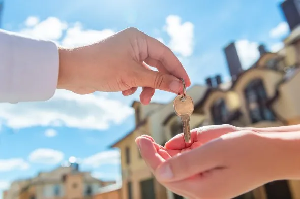Landlord handing keys to a renter, having determined how much to charge for rent.