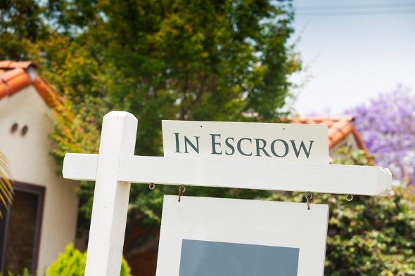 A sign on a home reading "in escrow."