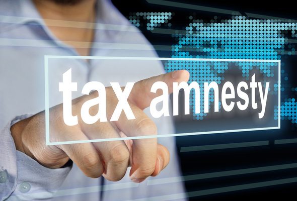 A man pointing to a word on a screen that says "tax amnesty."