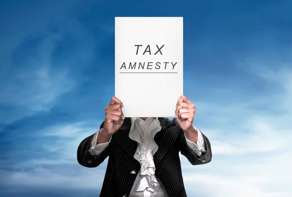 A man holding up a sign that says "tax amnesty."
