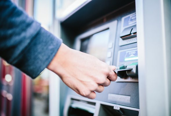 Closeup of a person inserting a card in an ATM.