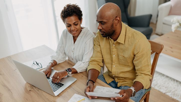 A married couple reviews various financial documents and information together in advance of creating a financial plan.