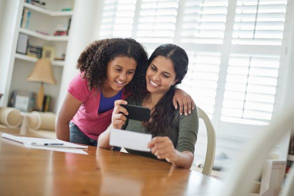 A mother and daughter depositing a check with a mobile app.