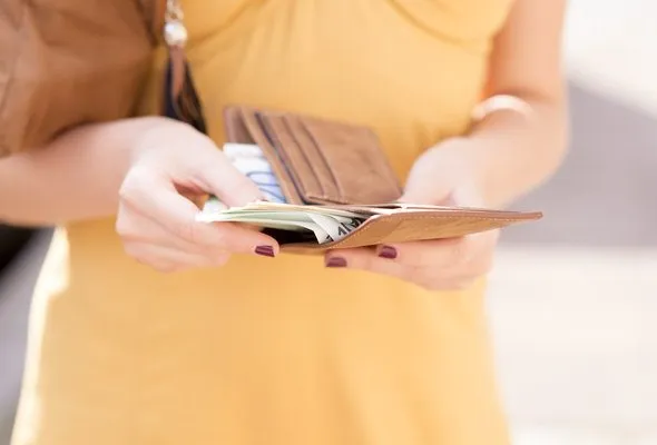 A woman counting how much money she has in her wallet.