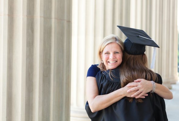 A mother hugging her daughter after graduating from college.