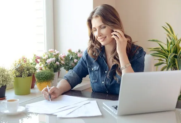 A woman reviewing tax documents with an accountant on the phone.