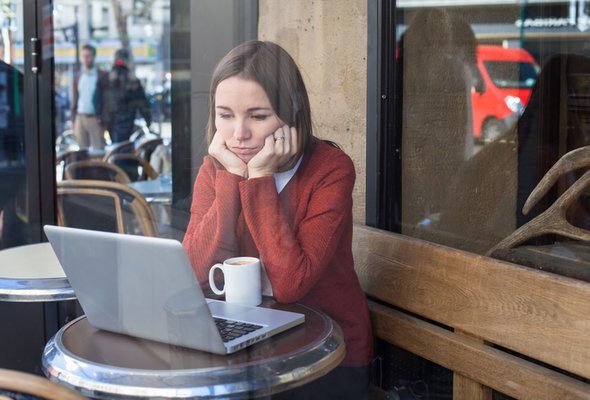 A woman at a coffee shop reviews her tax returns.