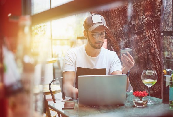A man on his laptop, researching prepaid debit cards.