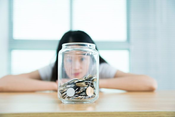 A young woman looking at a jar of change she's saved.