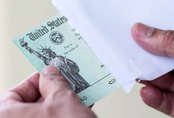 A close up of a tax refund check being pulled out of an envelope.
