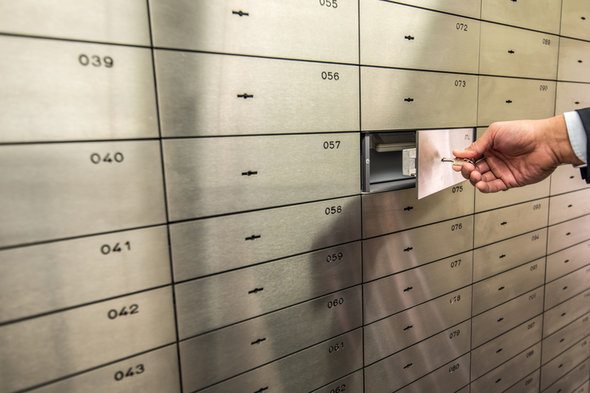 Closeup of a hand opening a safety deposit box.