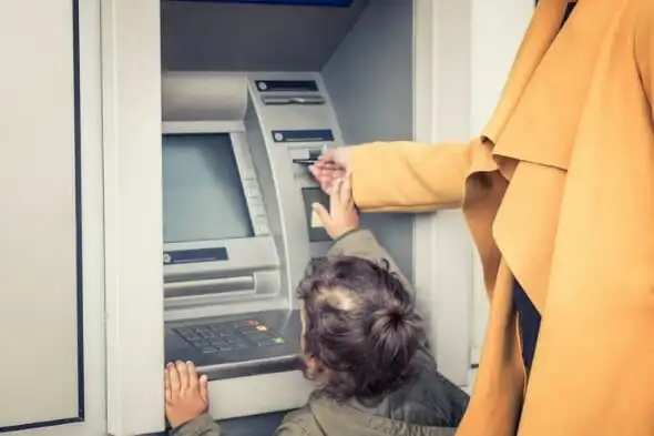 Closeup of a mother and her child at an ATM.