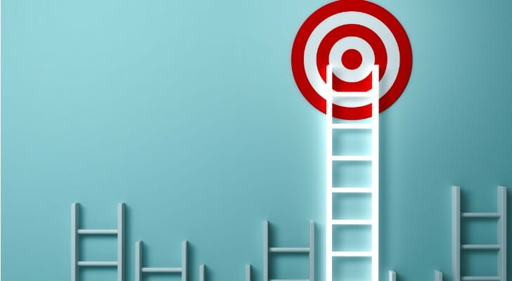 Ladders stacked against a wall, with one reaching a target.