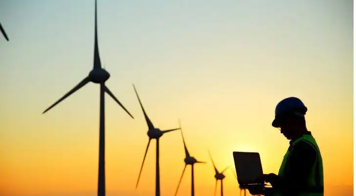 Wind turbines in front of a sunset.