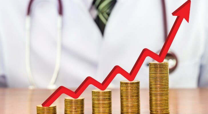 Stacks of coins lined up from shortest on the left to tallest on the right, and a red arrow trending upward.