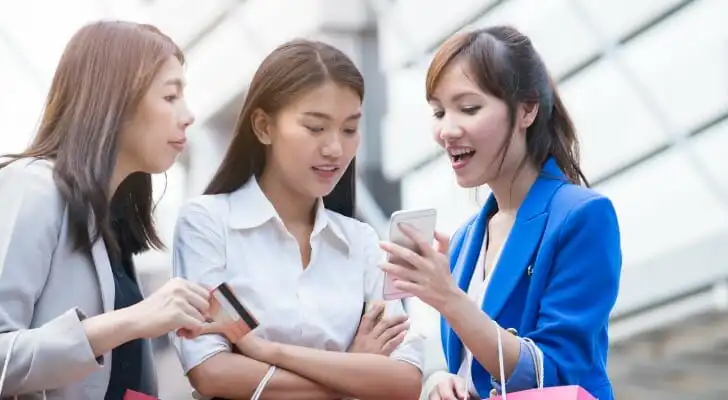 A group of girls use an app to transfer money.