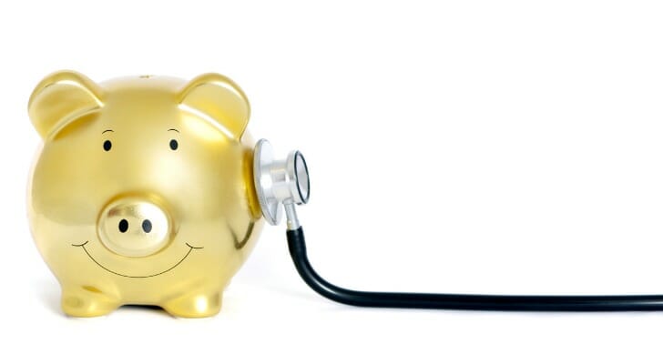 A stethoscope against a piggy bank.