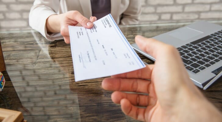 An employer handing a paycheck to an employee.