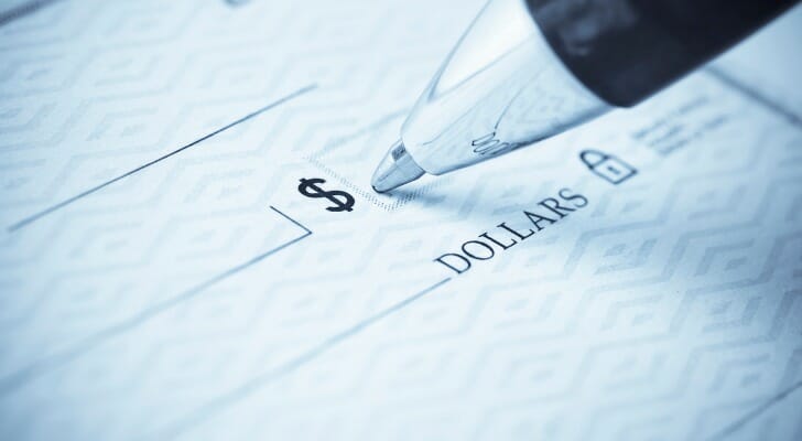 Closeup of a pen writing the amount on a check.