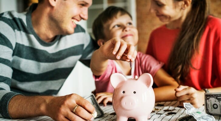 Family teaching son how to save with a piggy bank.