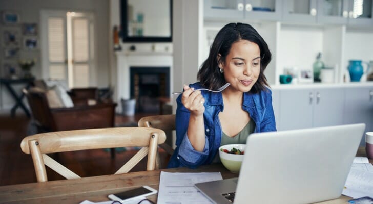 A woman relaxes and eats her breakfast, content in her choice to work with a financial advisor to invest $100,000.