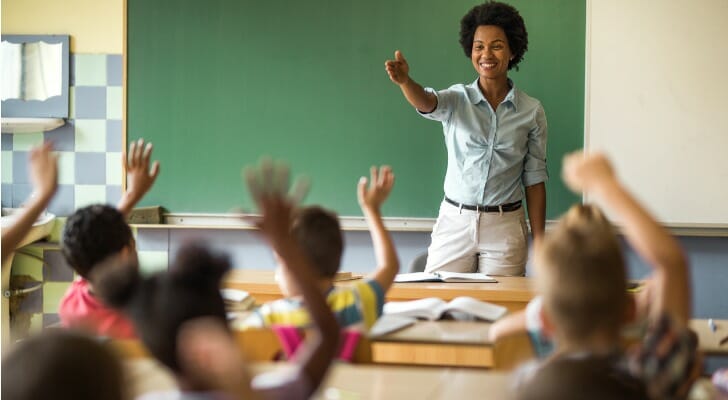 A teacher, who is eligible to contribute to a 403(b) plan, calls on a student.