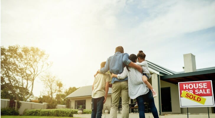 A family standing together in front of their new home.