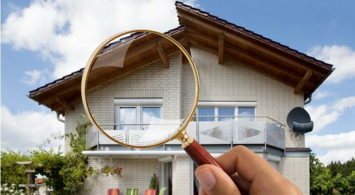A magnifying glass held in front of a house, symbolizing an FHA inspection and appraisal.