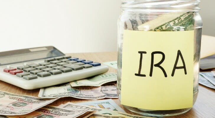 A glass jar with a yellow post-it labeled "IRA" to represent money set aside for contribution deadlines.