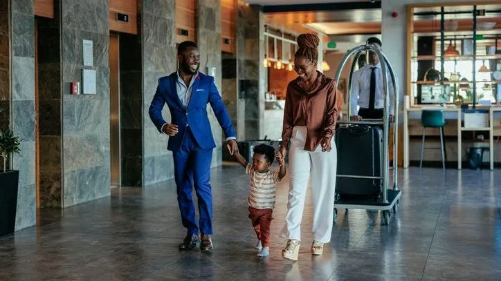 A pair of high-net-worth individuals walk with their son in the lobby of a hotel.