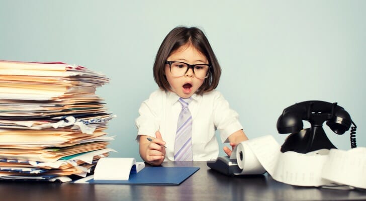 A child sitting at a desk with a phone and files.