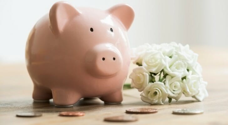 A piggy bank next to a wedding bouquet.