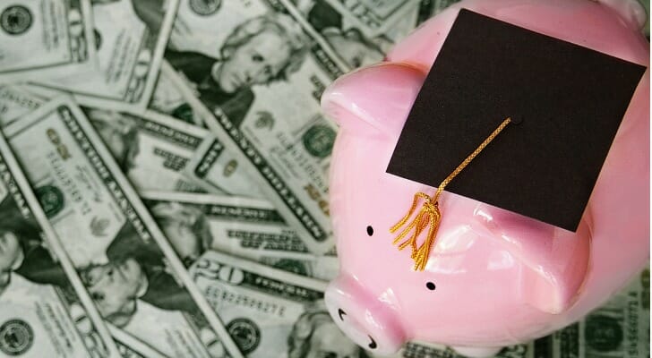 A piggy bank and cash, symbolizing discretionary income, which is used in conjunction with budgeting and student loans.