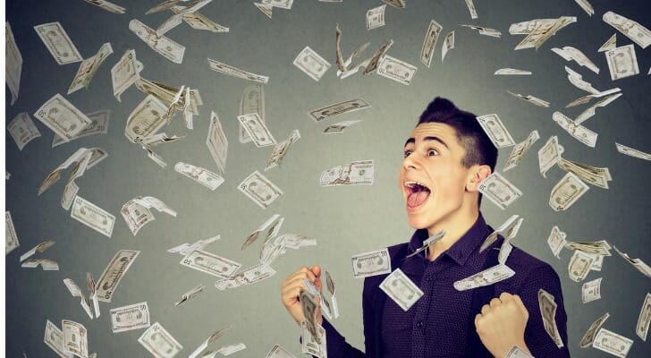 Money being showered down on a happy man.