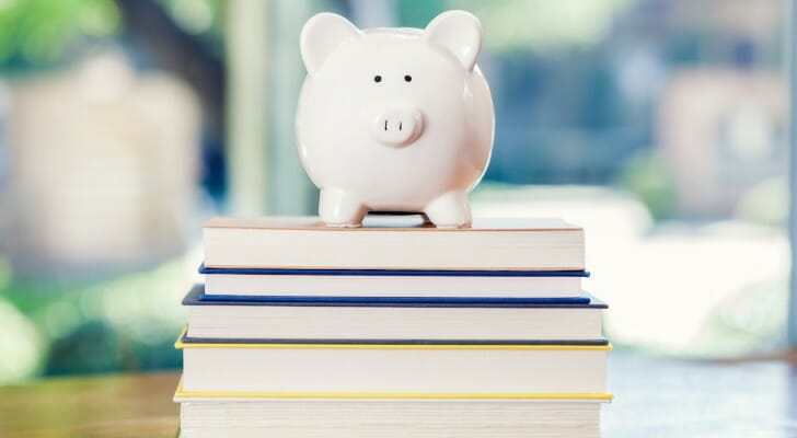 A piggy bank sitting atop a stack of books.