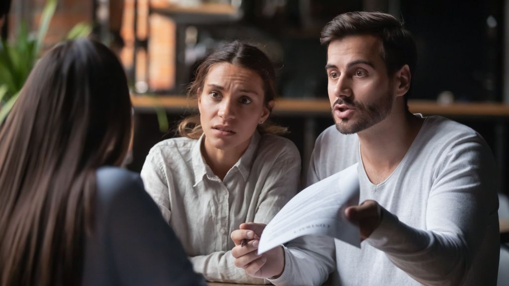 Angry customers confront a bank manager.
