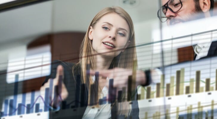Two advisors examine a price chart, discussing intrinsic value.