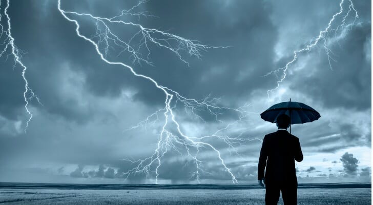 A business man watches a lightning storm, contemplating economic shocks.