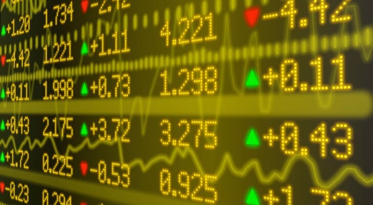Stock market ticker wall in yellow with various numbers and graphs