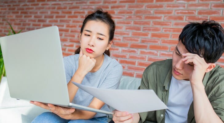 Two young people puzzle over the terms, conditions and costs of a variable annuity.